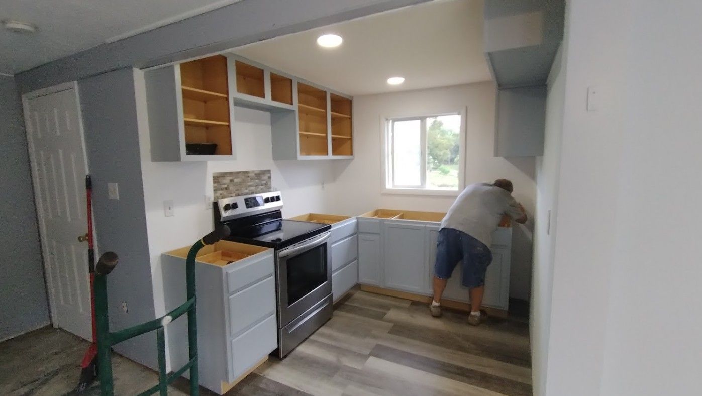 A man is working on a kitchen in a house.