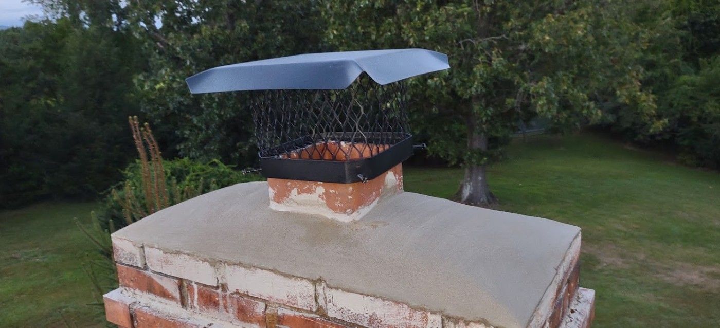 A brick chimney with a metal cap on top of it.