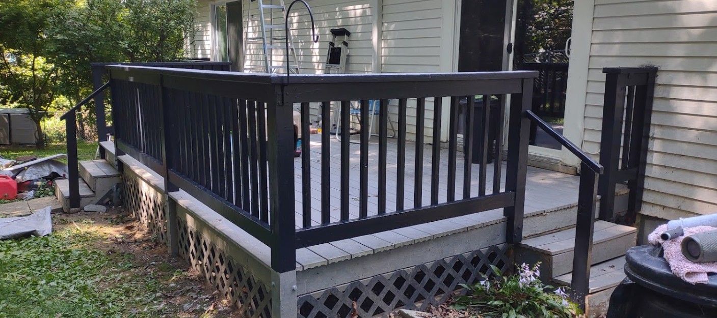 A white house with a black deck and stairs.