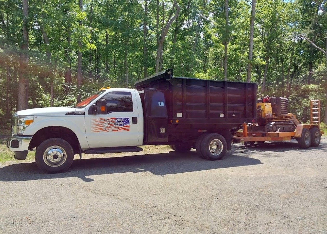 A dump truck is parked on the side of the road next to a trailer.