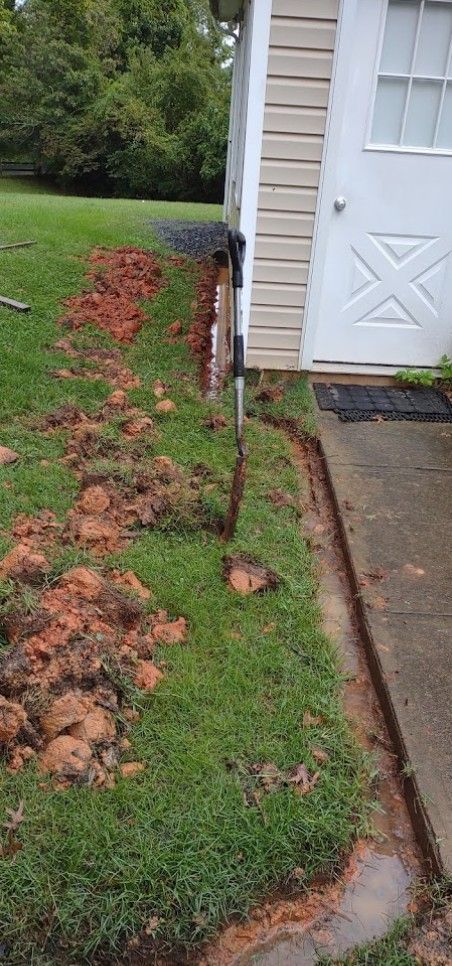 A shovel is sitting in the grass next to a house.