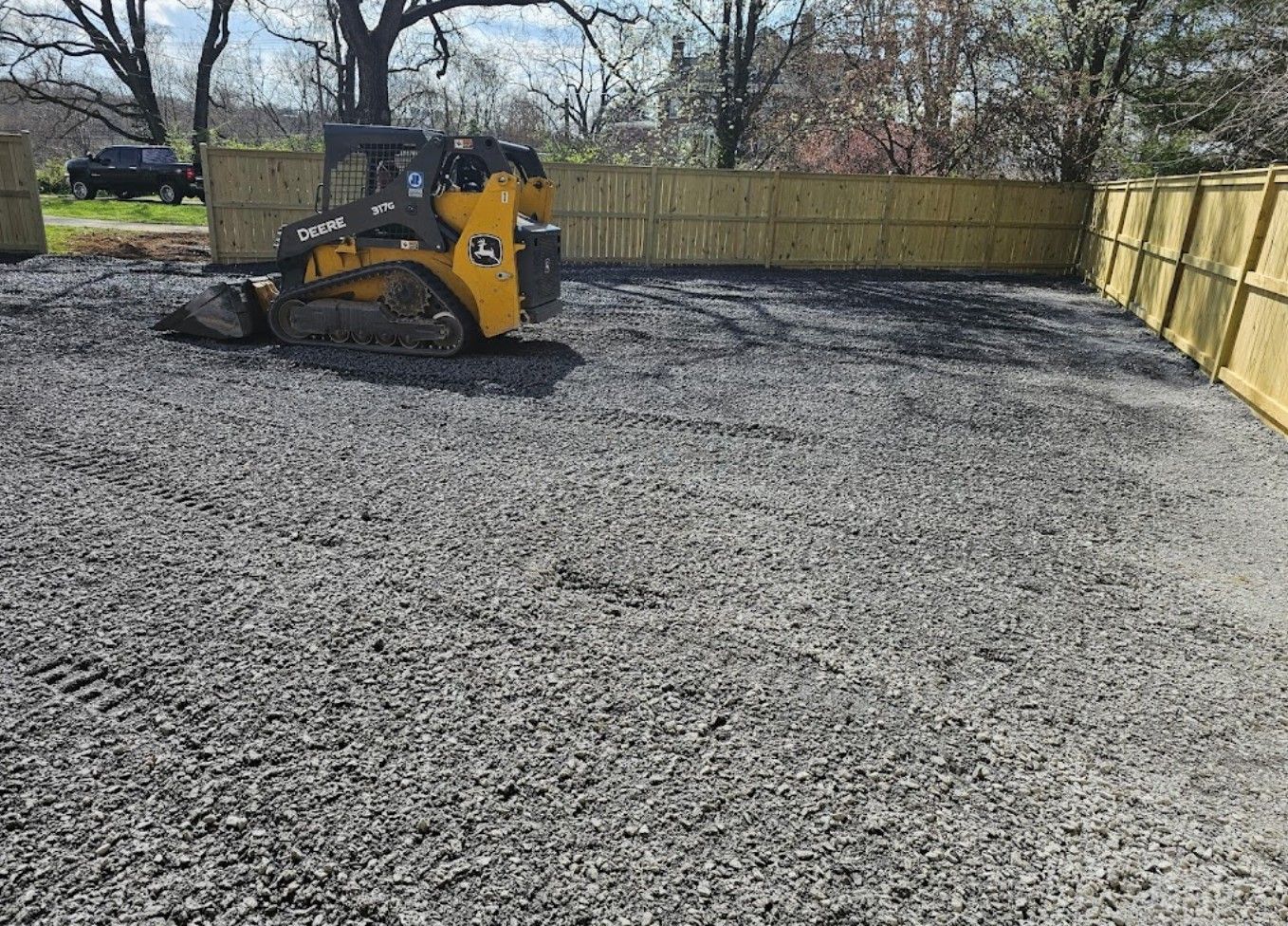 A yellow and black tractor is parked in a gravel lot.