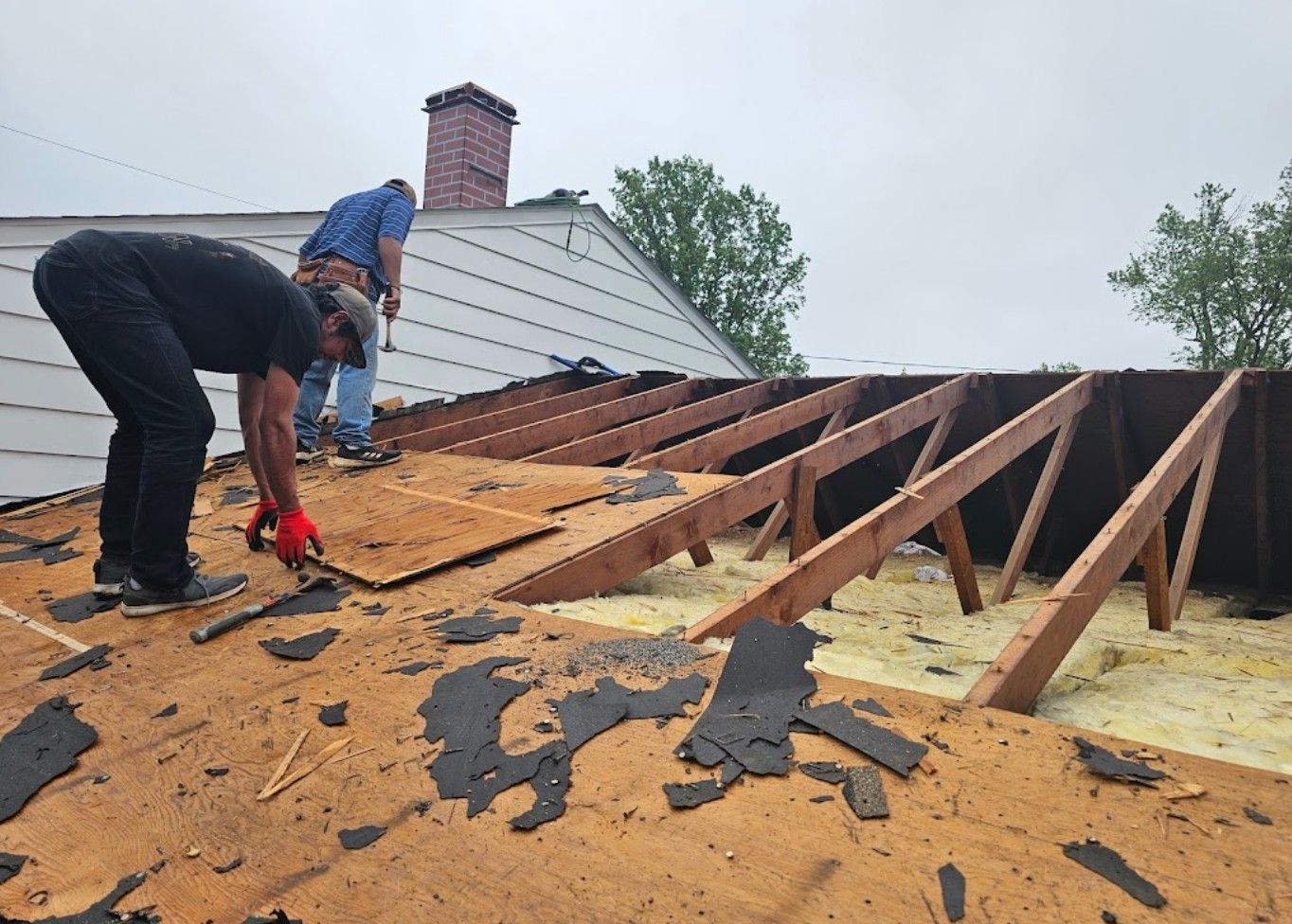 Two men are working on the roof of a house.