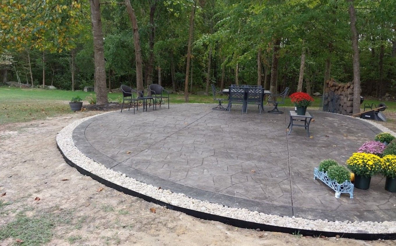 A circular patio with a table and chairs in the middle of a forest.