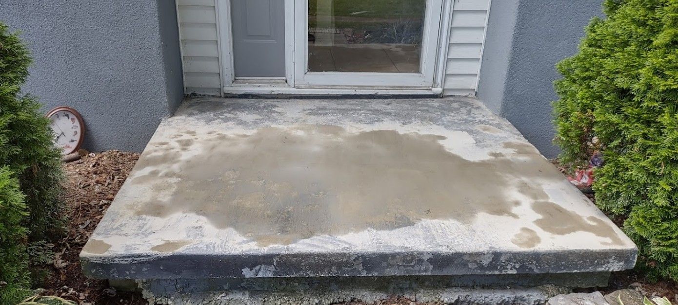 A concrete porch with steps leading to a door.