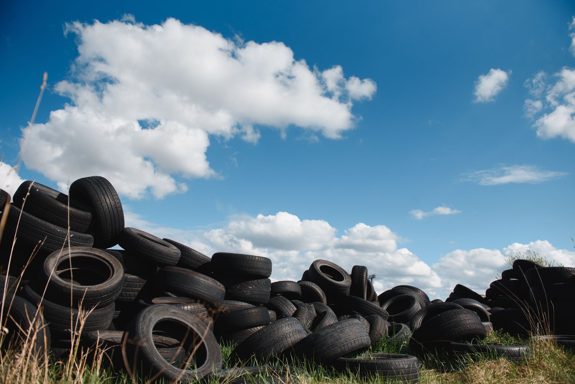 Truck dumping a pile of used tires in a waste disposal facility.