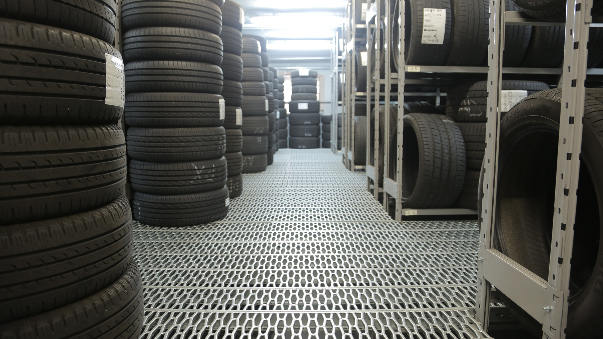 Stacks of used tires outside a shop on a sunny day.