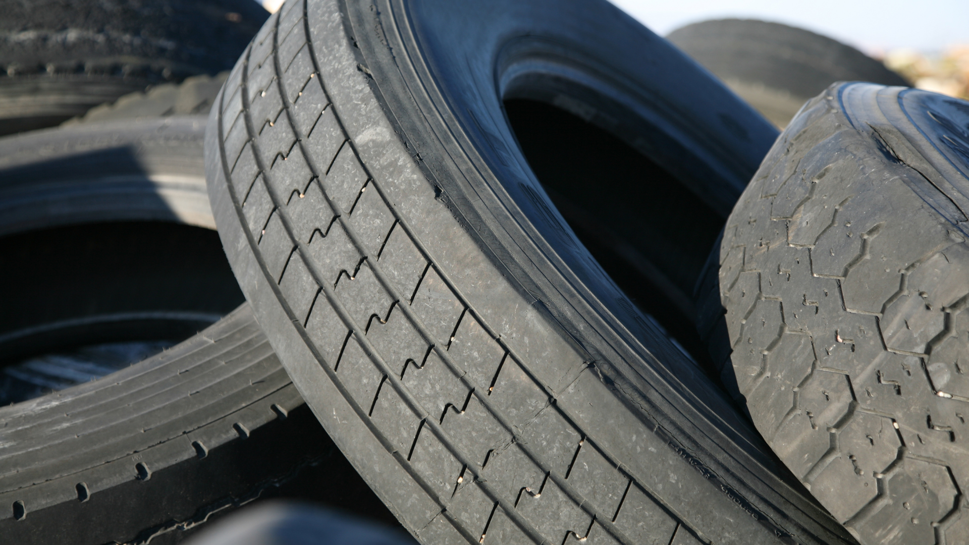 Stacks of used tires, tightly bound, outdoors.