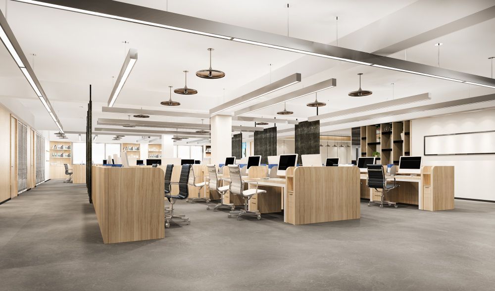 Modern open-plan office with desks, chairs, and wood partitions under bright ceiling lights
