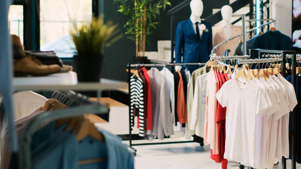 Clothing store with racks of shirts and jackets, and mannequins near a bright display area
