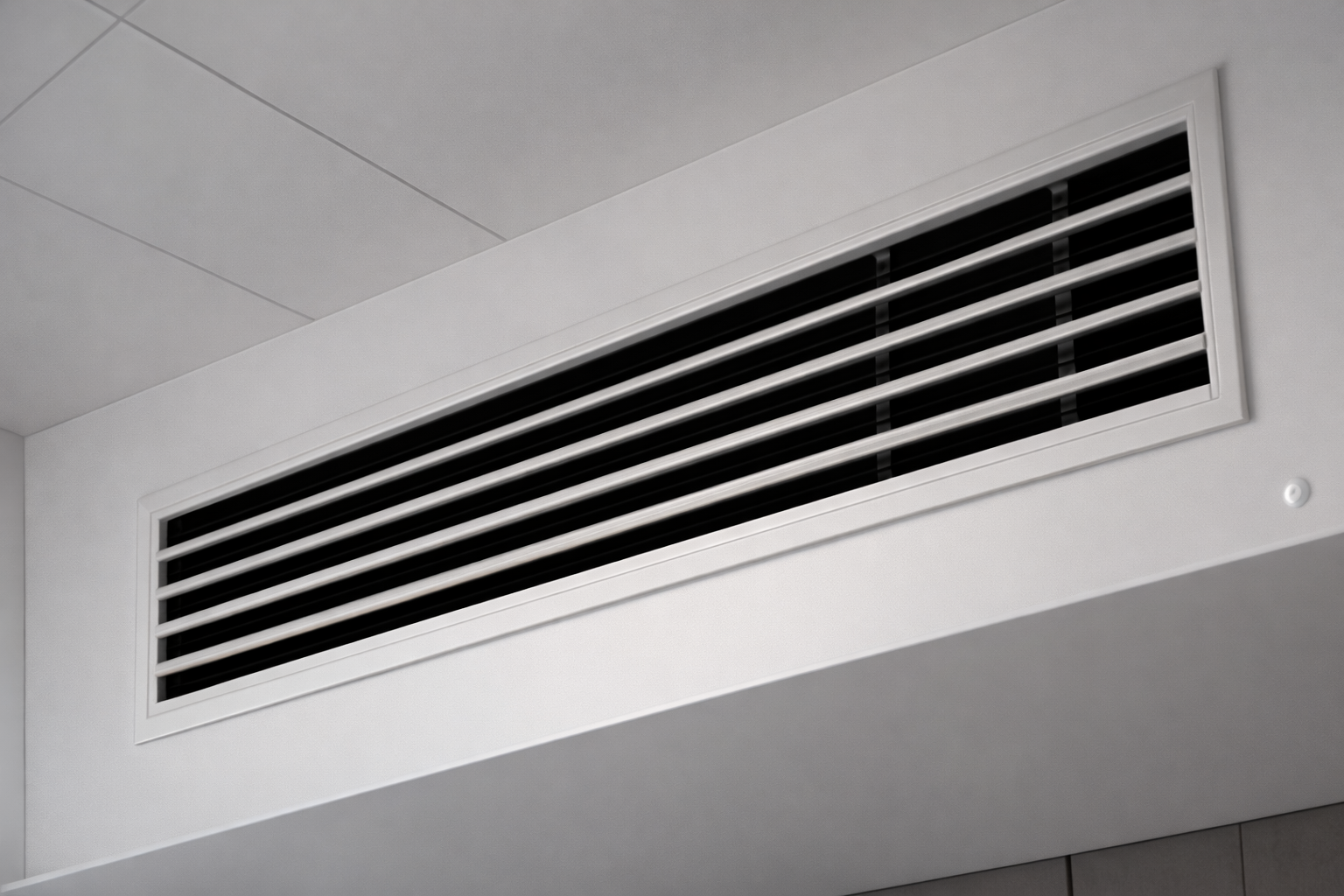 White ceiling vent with black horizontal slats near a corner