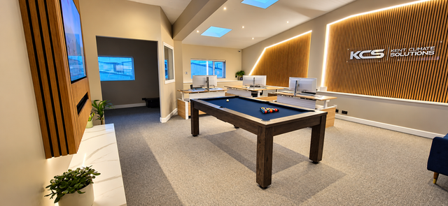 Modern conference room with wood tables, black chairs, floor-to-ceiling windows, and a ceiling-mounted AC unit