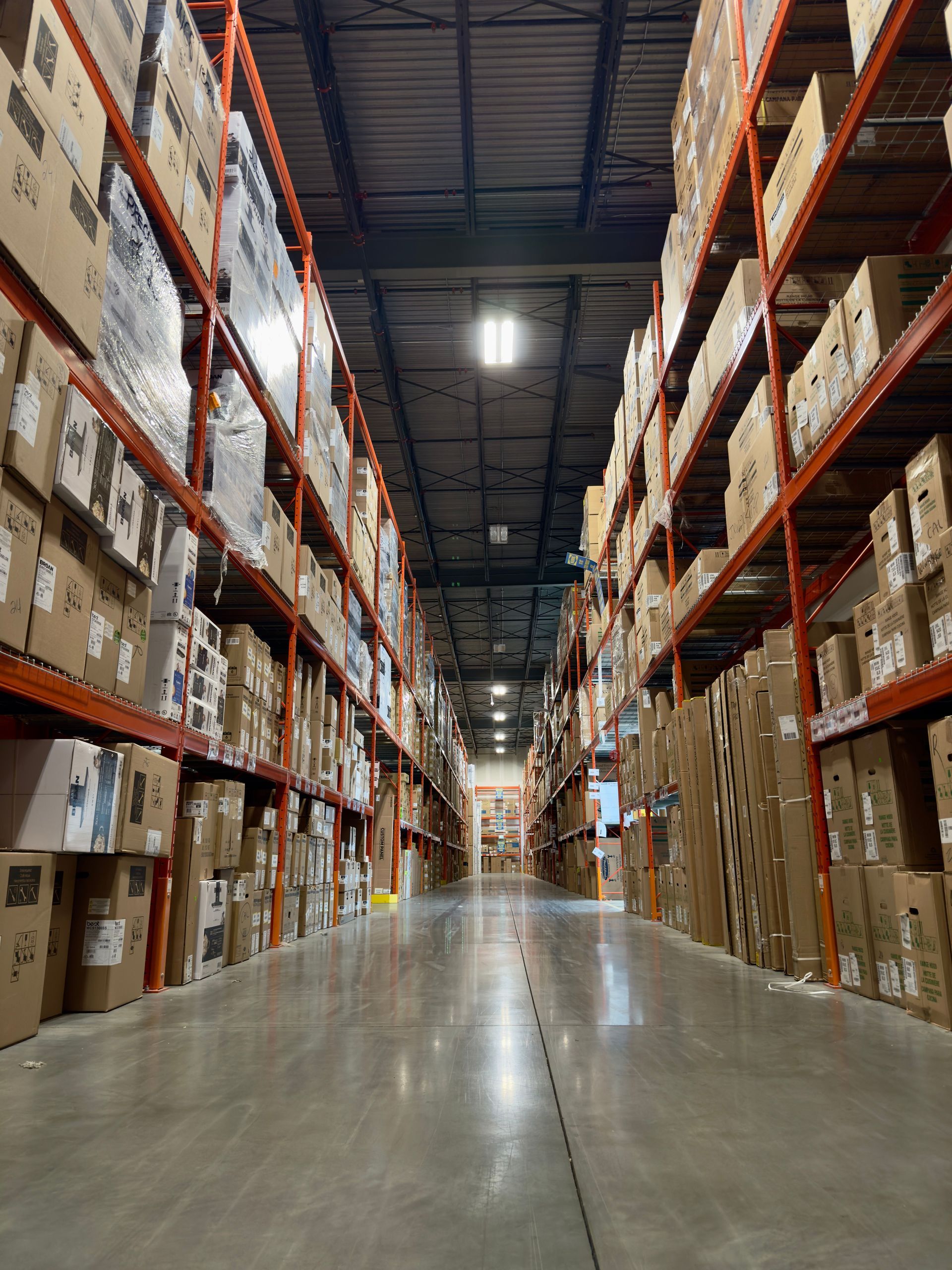 Aisle in a large warehouse with tall pallet racks stacked with boxes on both sides