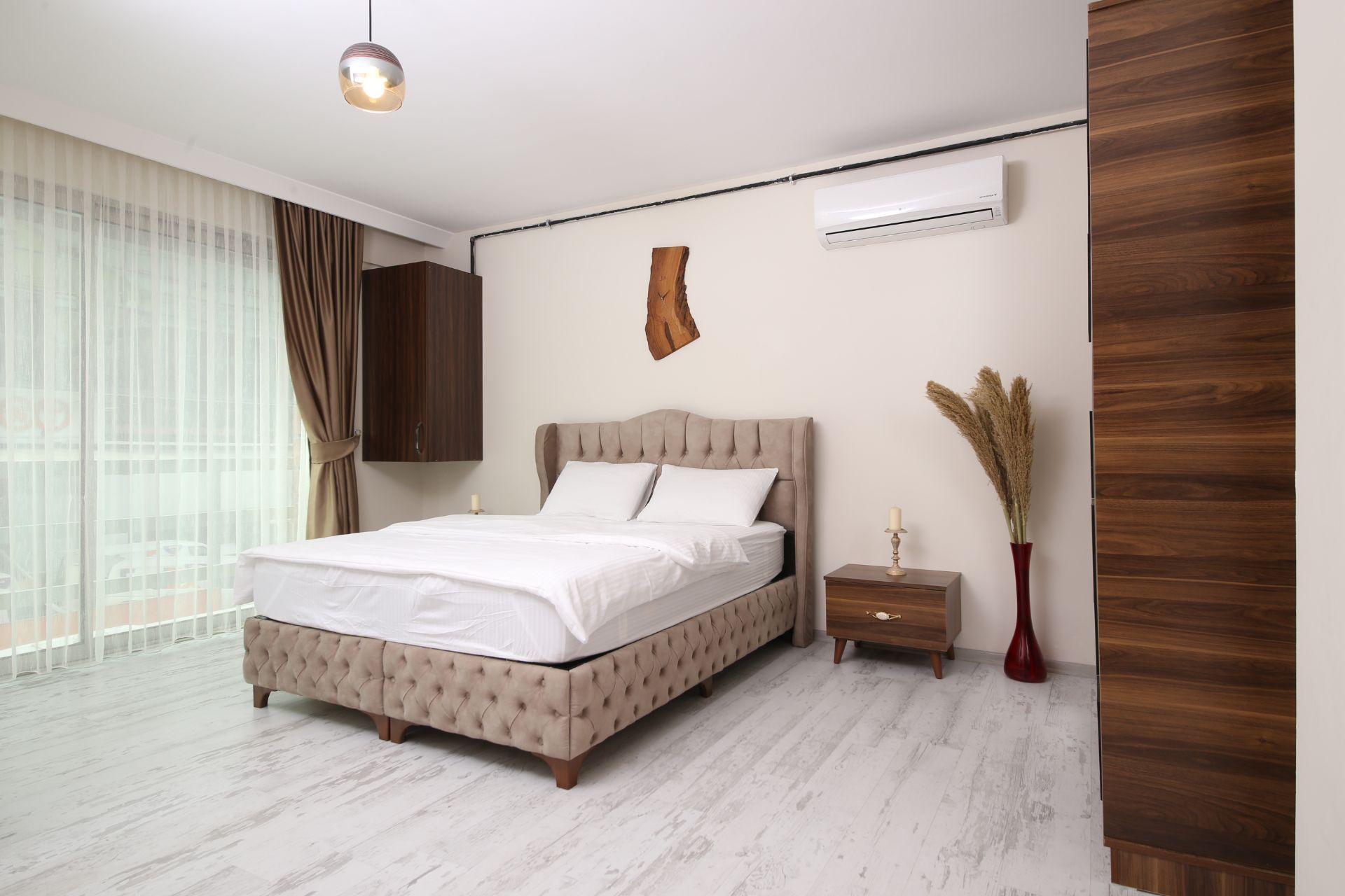 Bright modern bedroom with a white bed, wood accents, curtains, and air conditioner