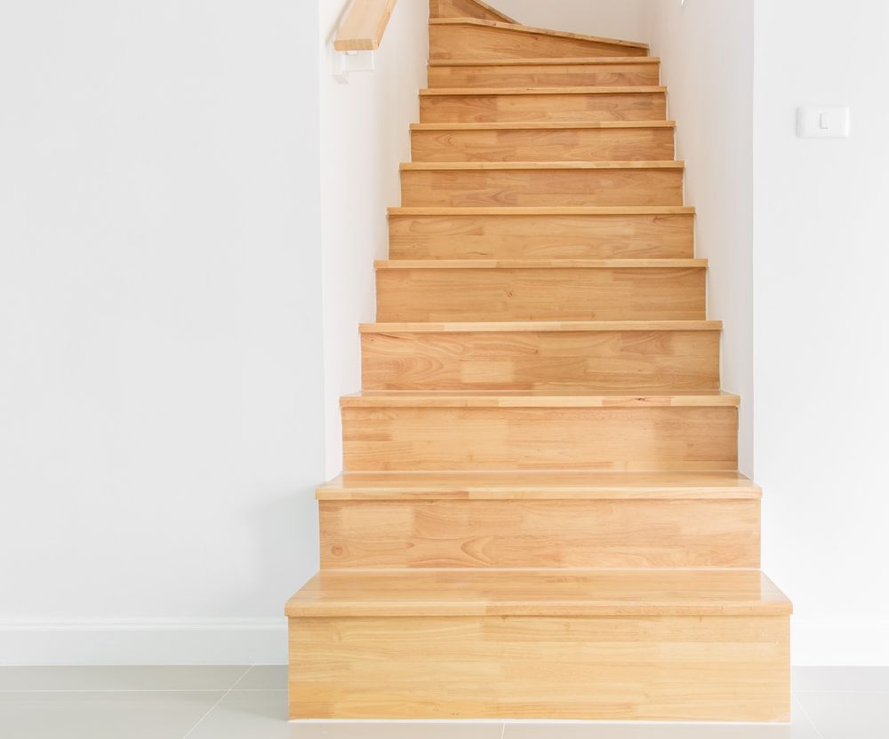 A Wooden Staircase in an Empty Room With a White Wall — Maroochy Floor Sanding in Coolum, QLD