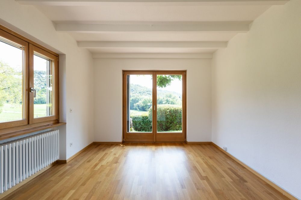An Empty Room With Hardwood Floors and Sliding Glass Doors — Maroochy Floor Sanding in Maroochydore, QLD