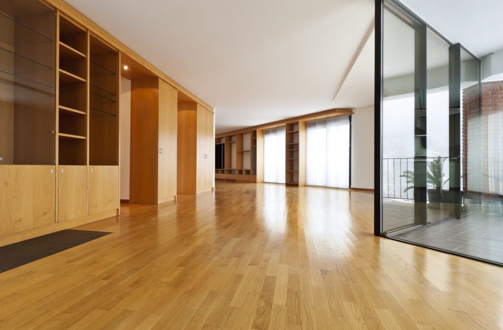 A Large Empty Room With Hardwood Floors and Lots of Windows — Maroochy Floor Sanding in Noosa, QLD