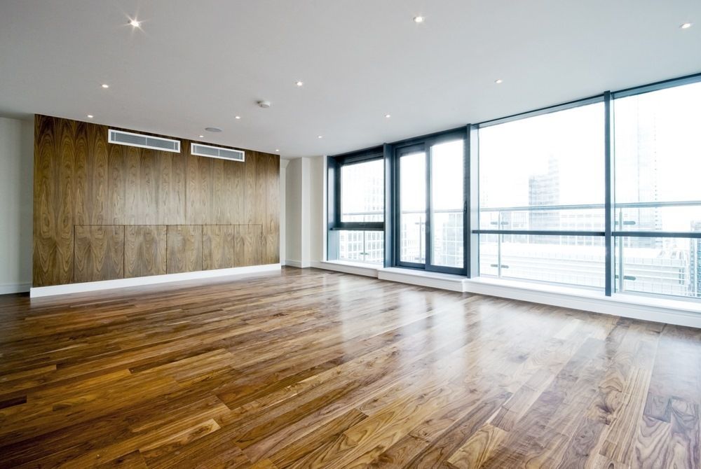 An Empty Living Room With Hardwood Floors and Lots of Windows — Maroochy Floor Sanding in Nambour, QLD