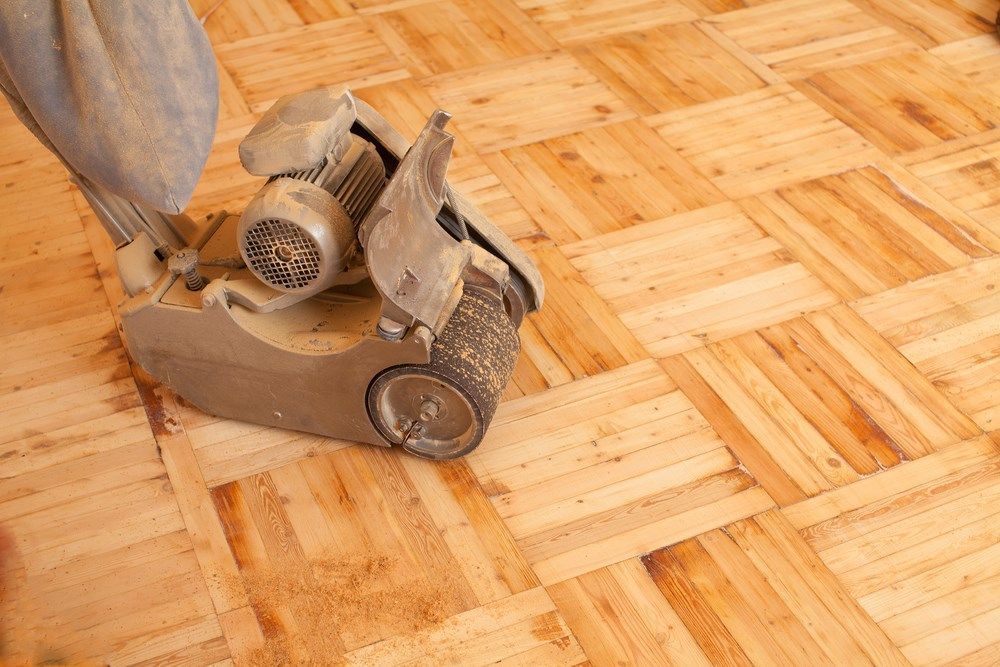 A Person is Sanding a Wooden Floor With a Machine — Maroochy Floor Sanding in Nambour, QLD