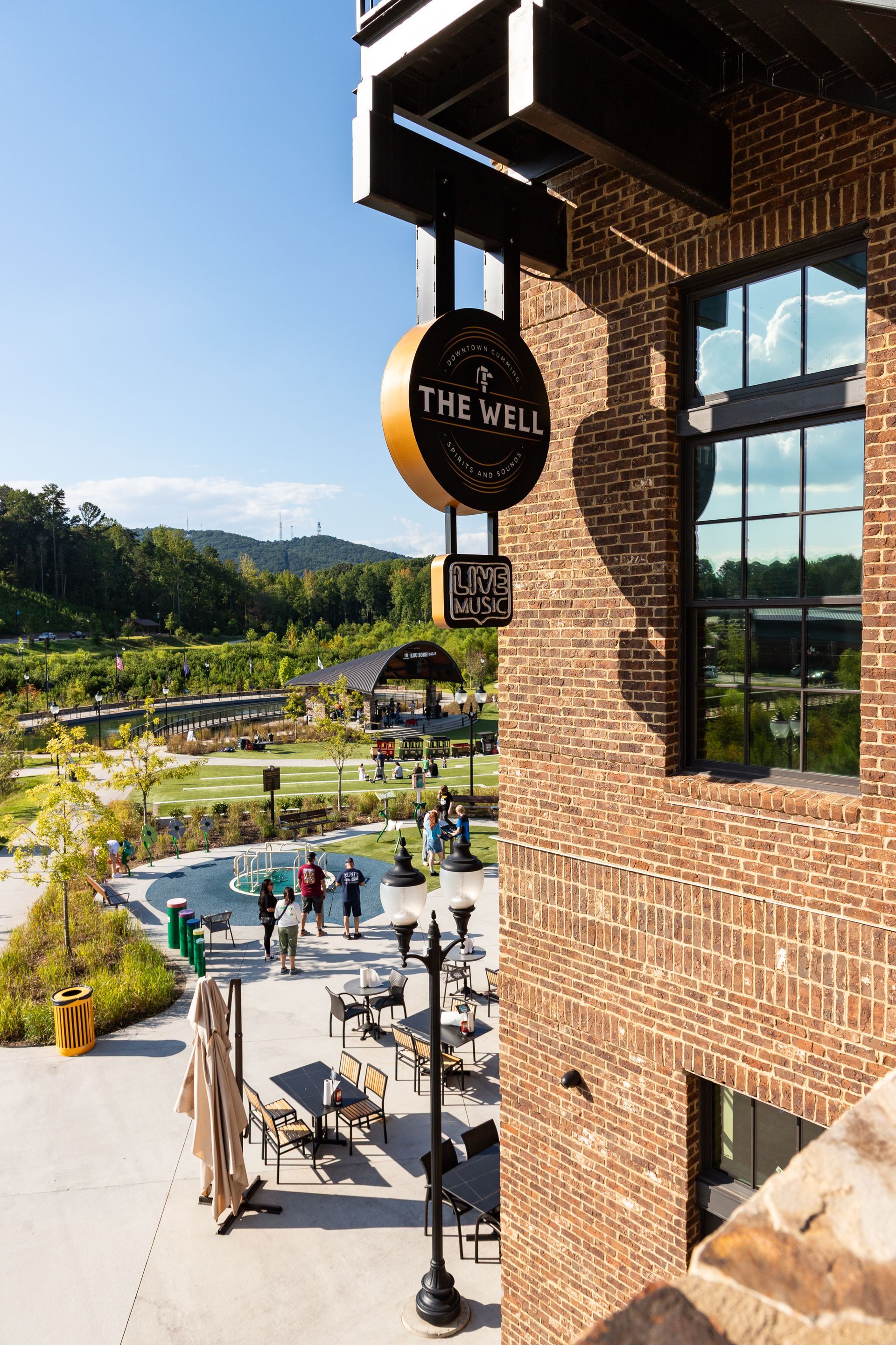 Brick building overlooking an outdoor pool and patio with mountains in the background.