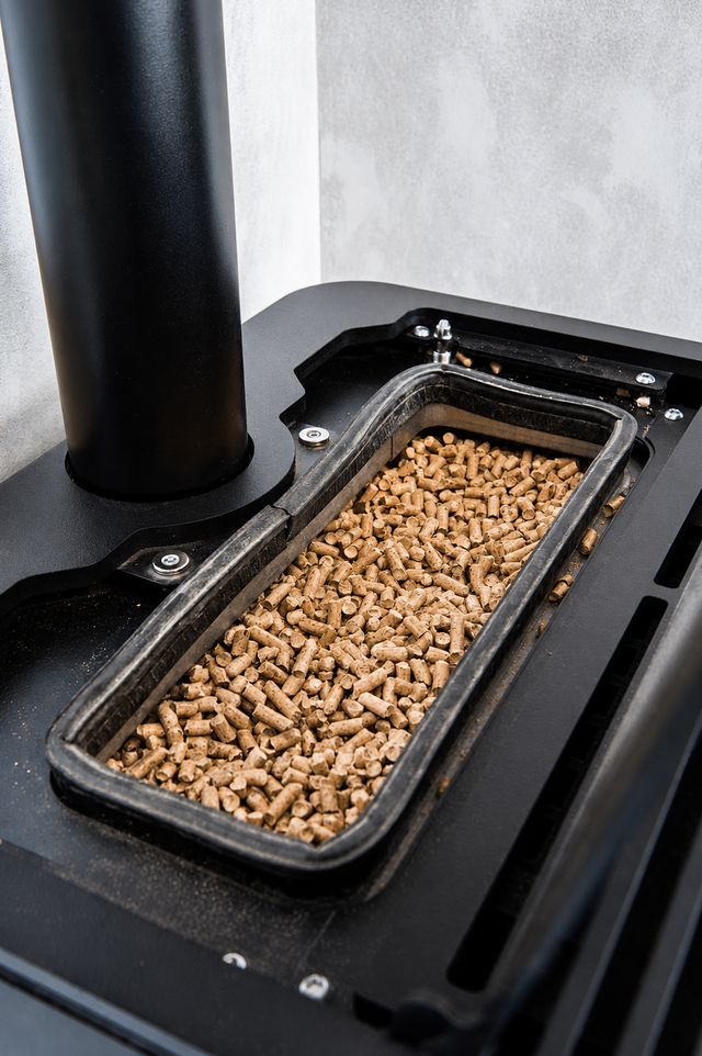 Black pellet stove hopper filled with wood pellets, shown close up.