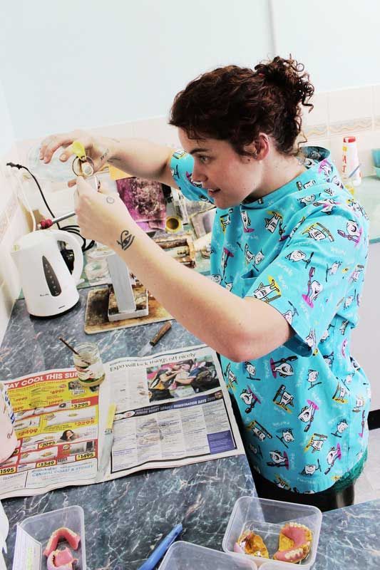 Kyrah in Clinic holding a measure cup and working on new denture moulds — Dentures in Toukley, NSW