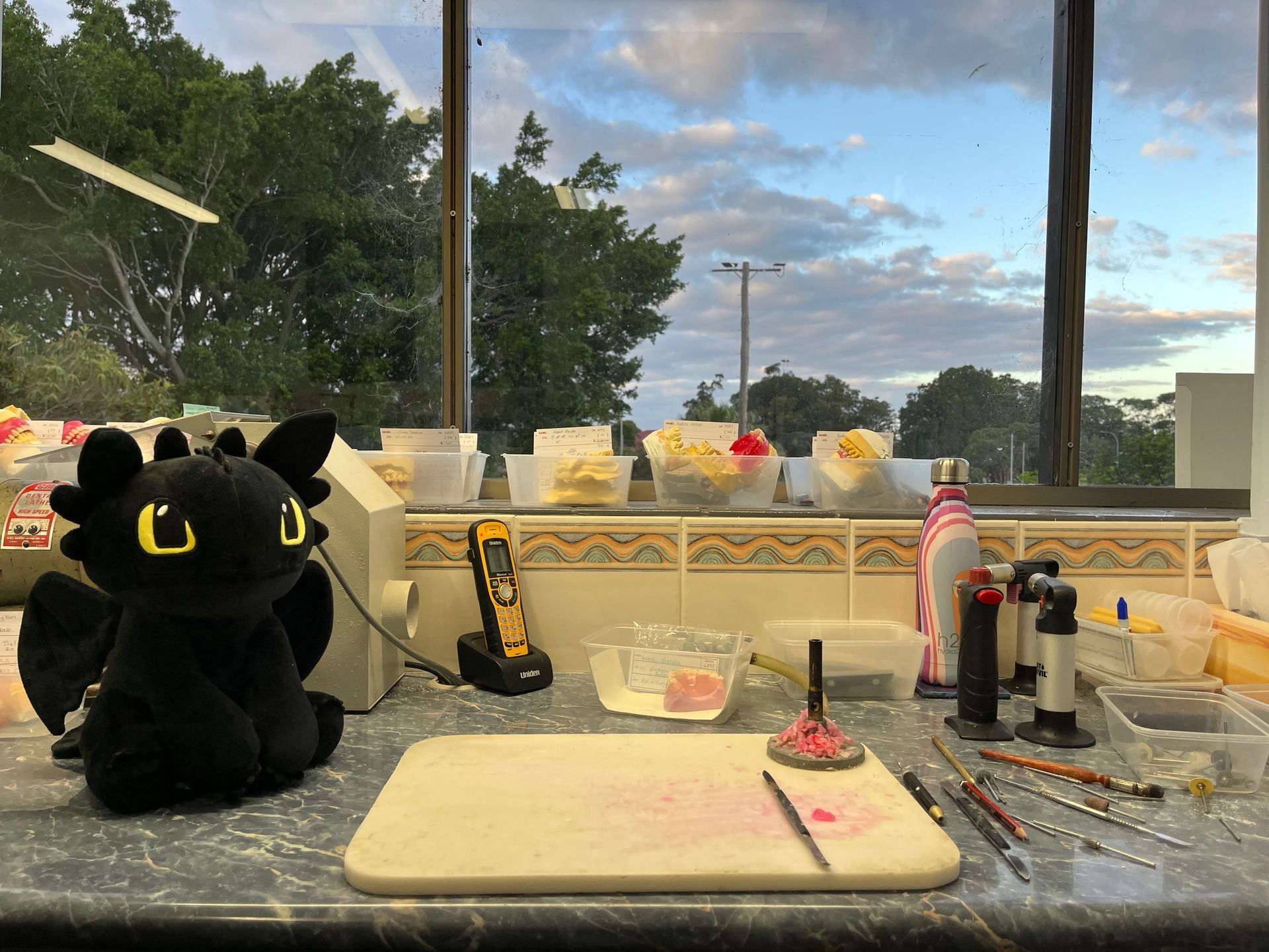 White chopping board with black dragon plushie on the left side with craft tools - Dentures in Toukley, NSW