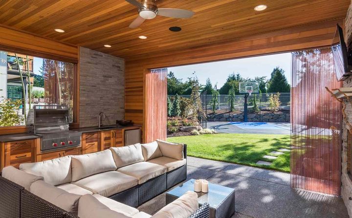 Covered patio with sectional sofa, bar counter, and open view to a sunny backyard and pool