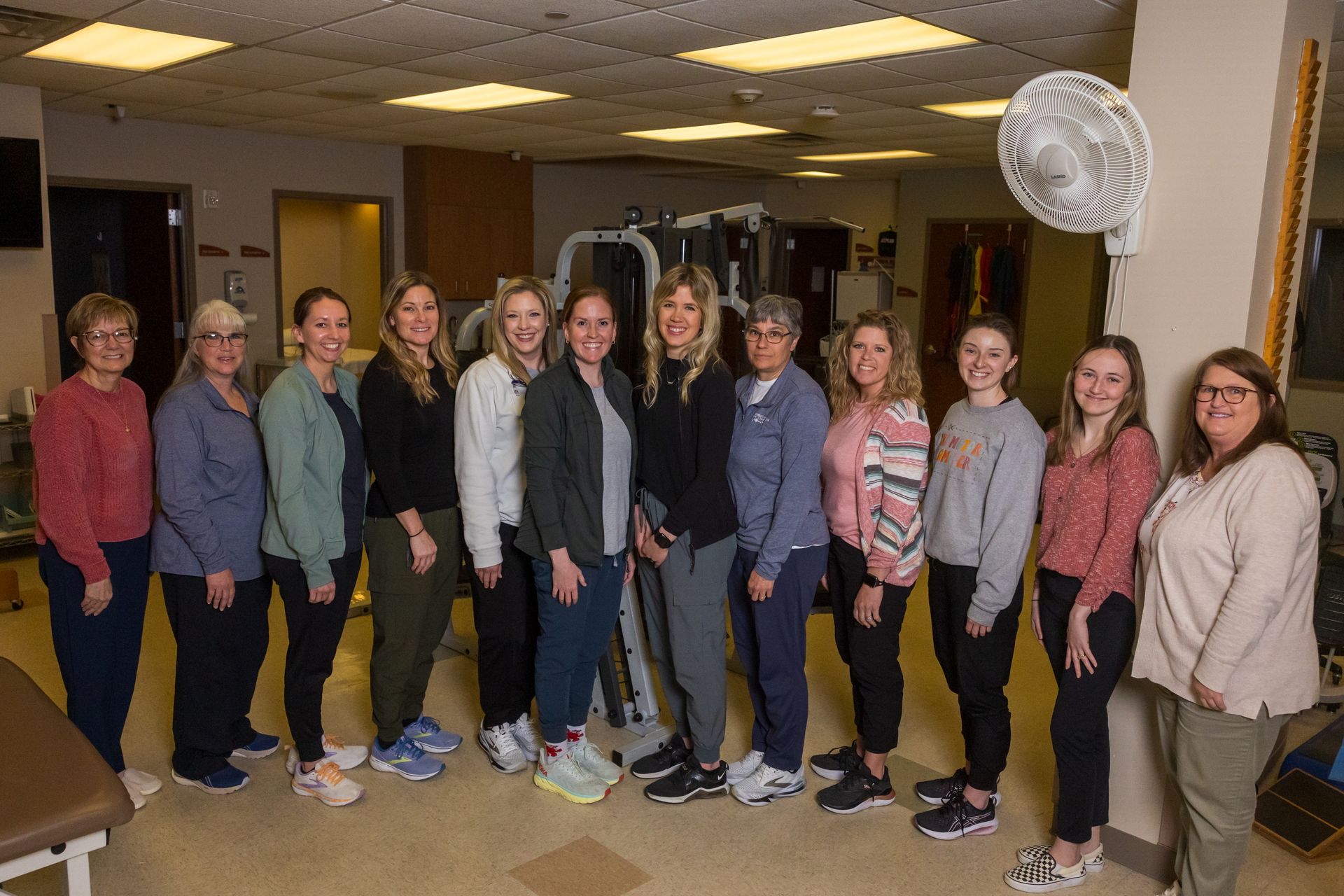 Group of women smiling in a physical therapy clinic. Exercise equipment in background.