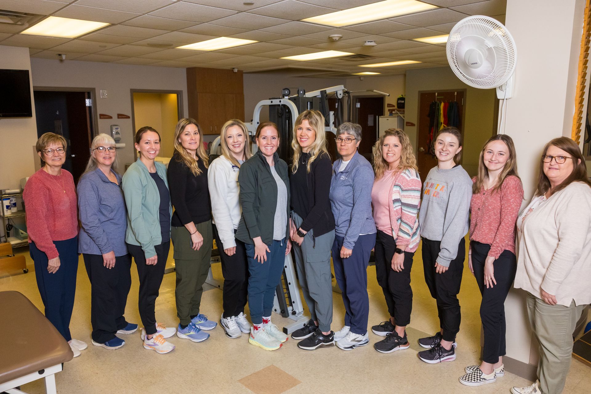 A group of ten healthcare workers standing in a clinic setting. They are wearing casual clothing.