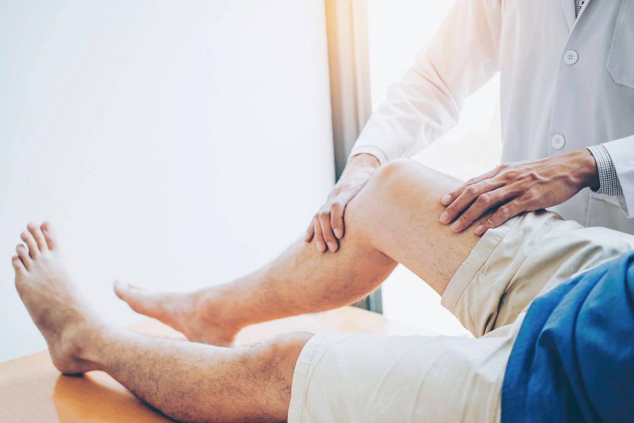 A doctor is examining a patient 's knee in a hospital.