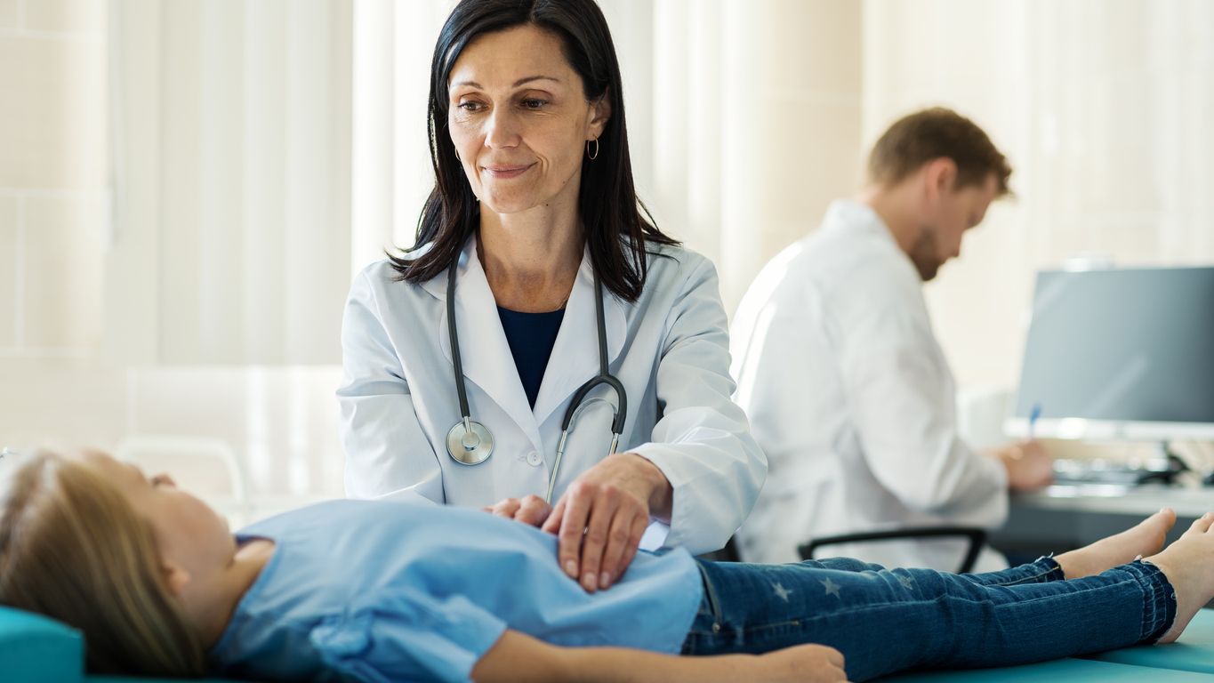 A person is pointing at an EKG monitor with a heartbeat on it.