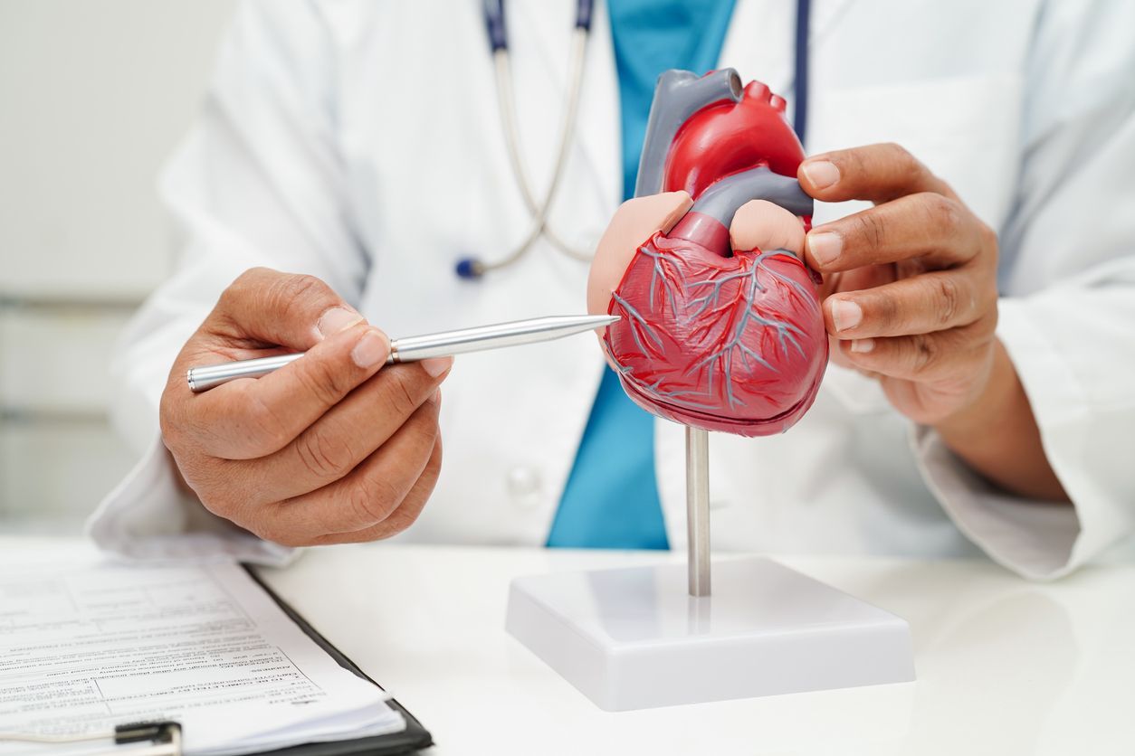 A doctor is writing on a clipboard next to a laptop and a stethoscope.