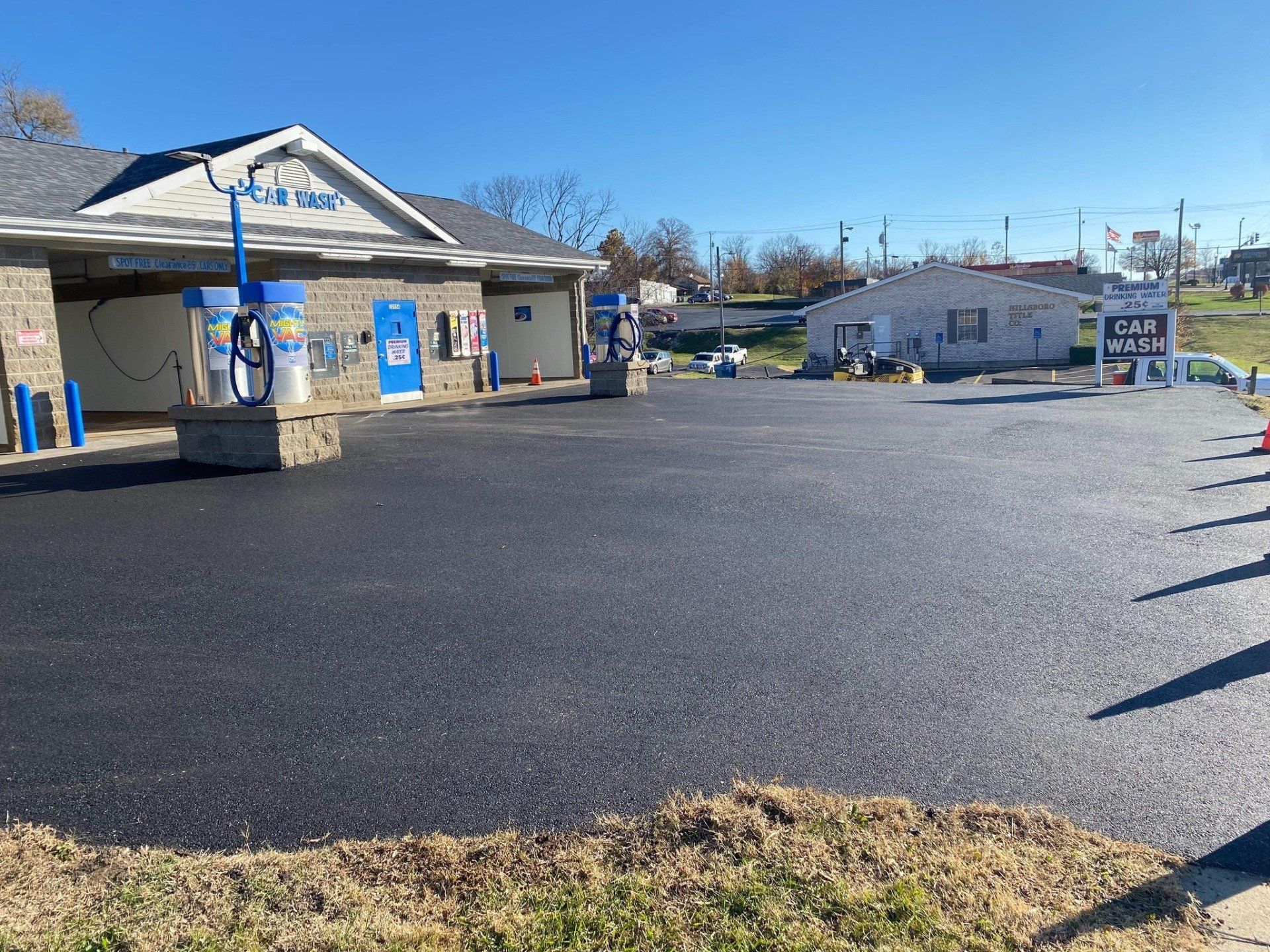 Gas station convenience store with blue trim and a large empty asphalt lot under a clear sky