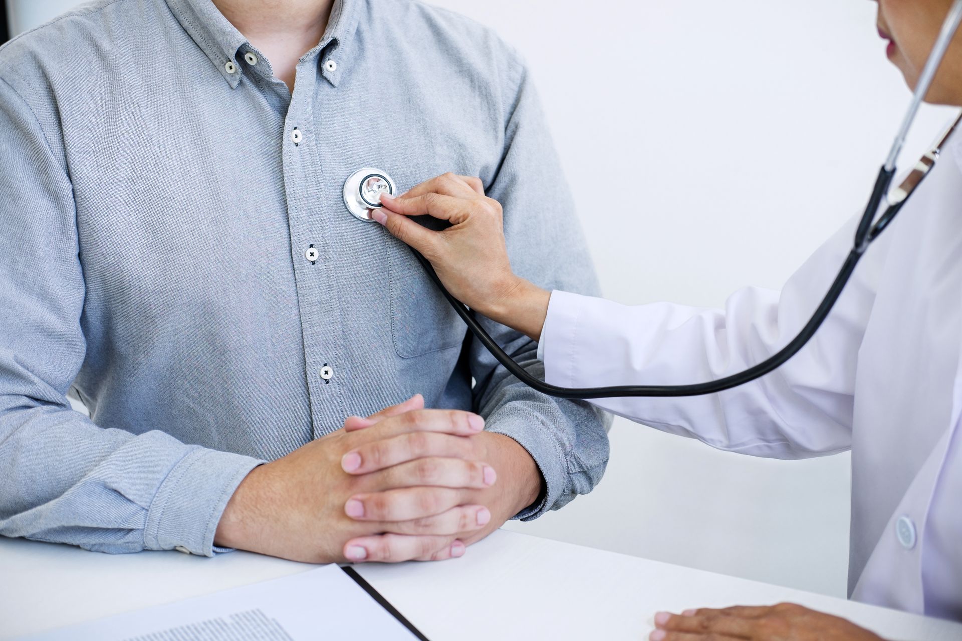 A doctor is listening to a patient 's heart with a stethoscope.