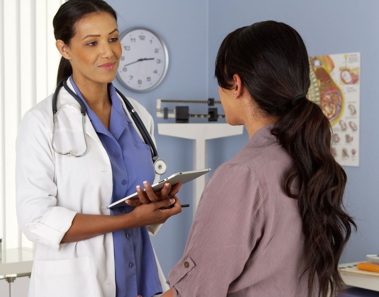 A doctor is talking to a patient who is holding a tablet