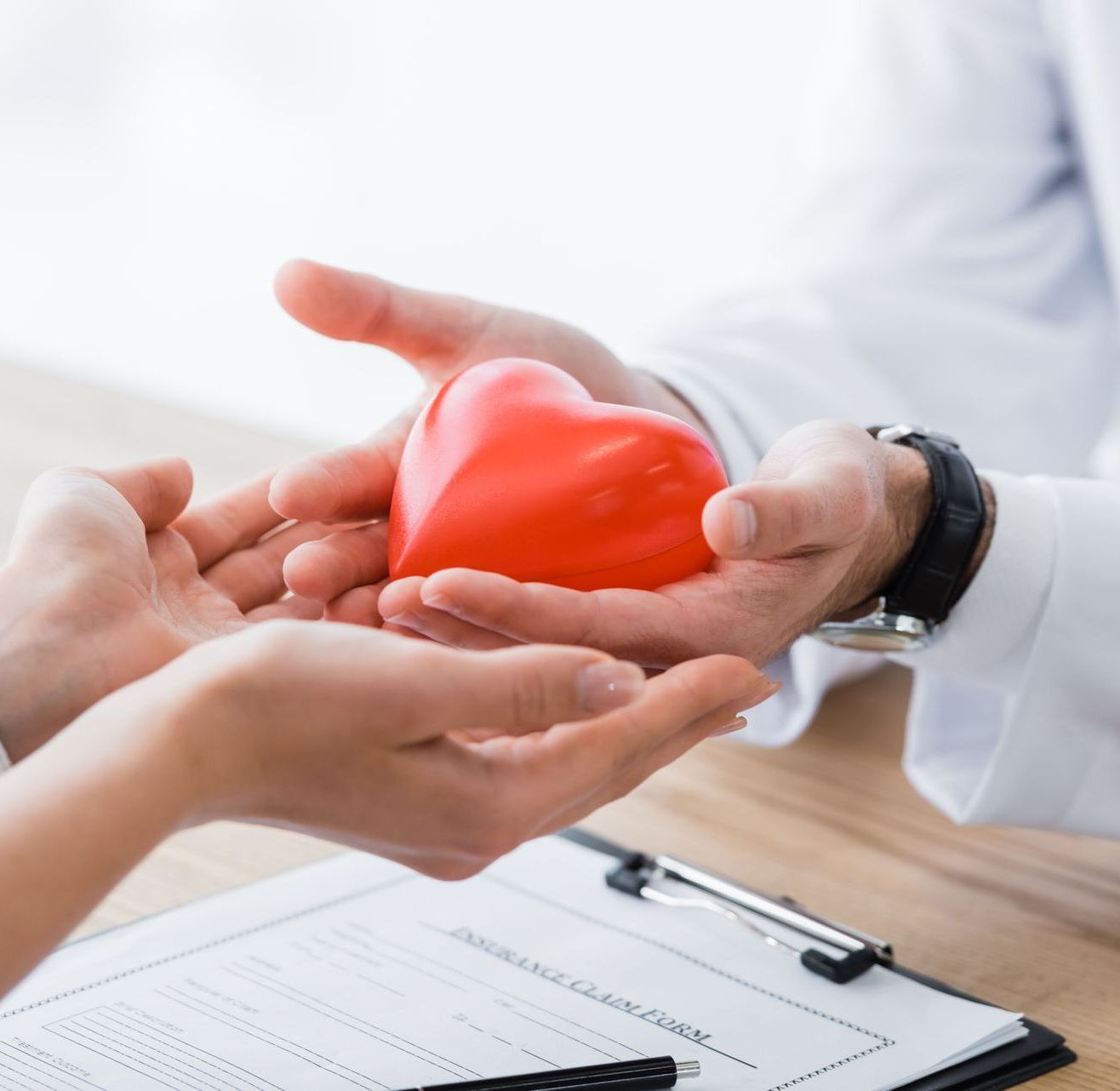A person is holding a red heart in their hands