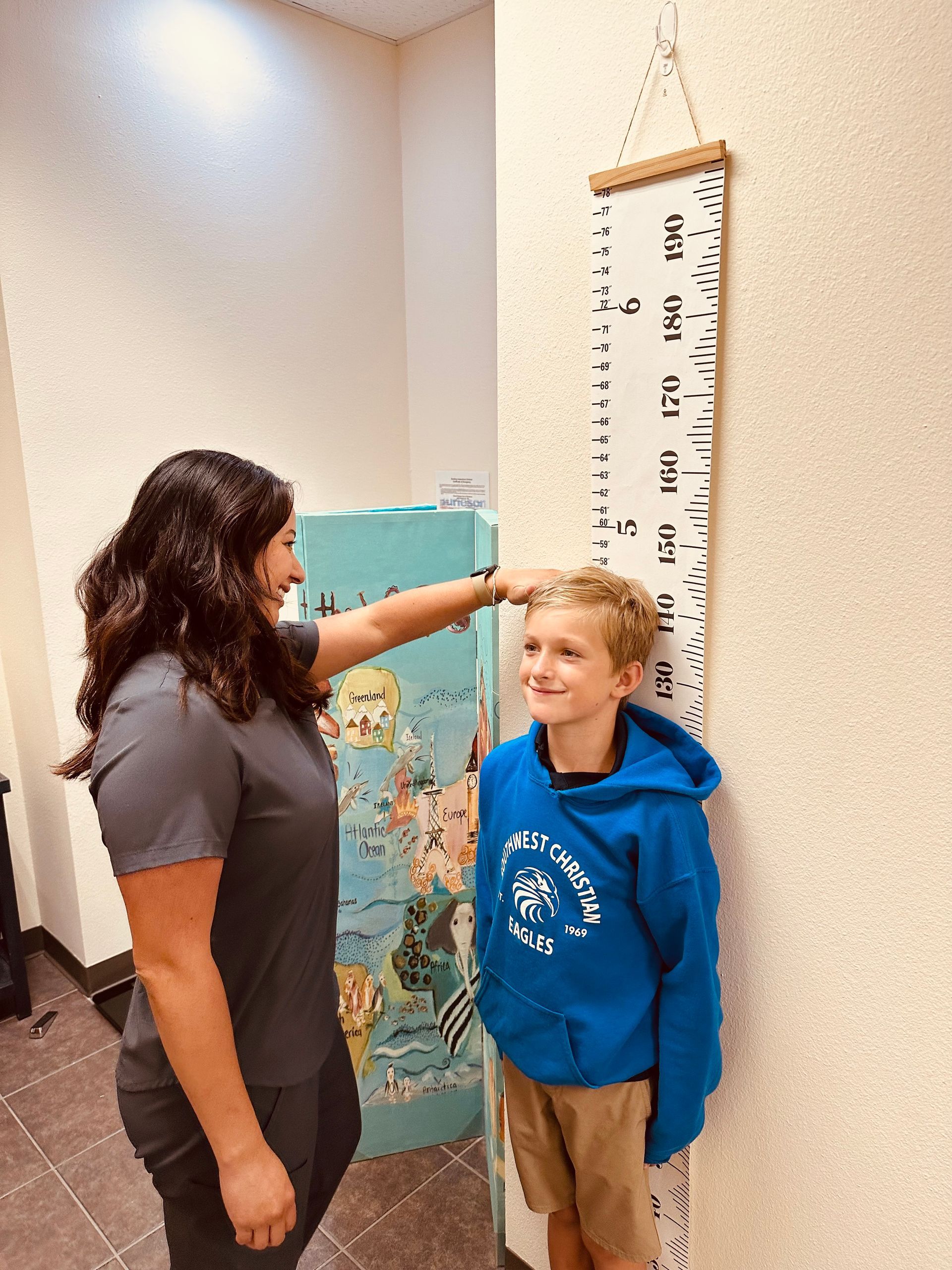 A woman is measuring a boy 's height with a ruler.