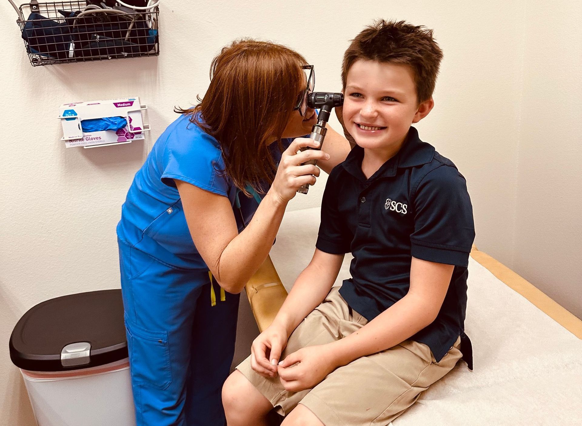 A woman is examining a young boy 's ear with an otoscope.