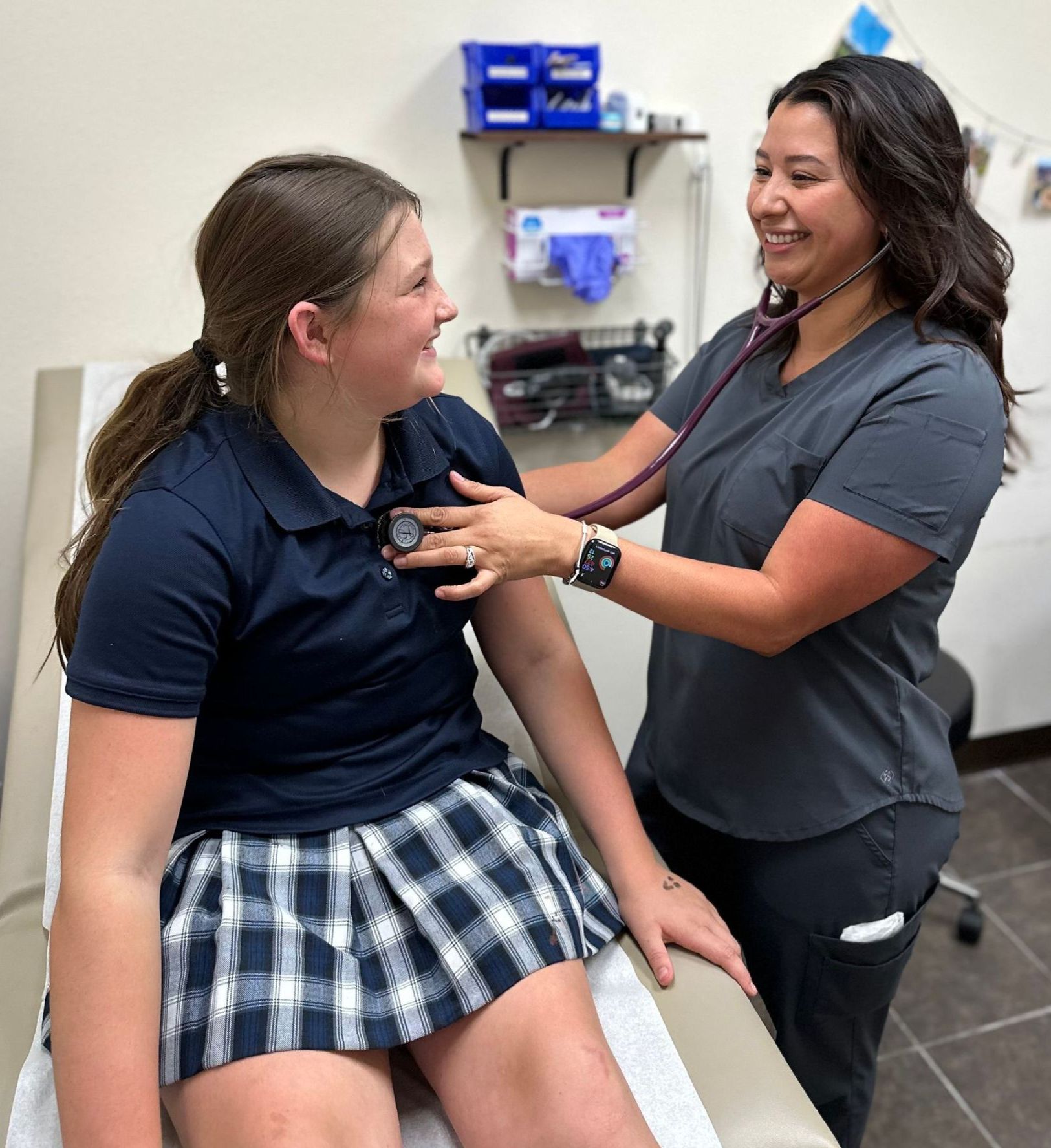 A woman is listening to a girl 's heartbeat with a stethoscope