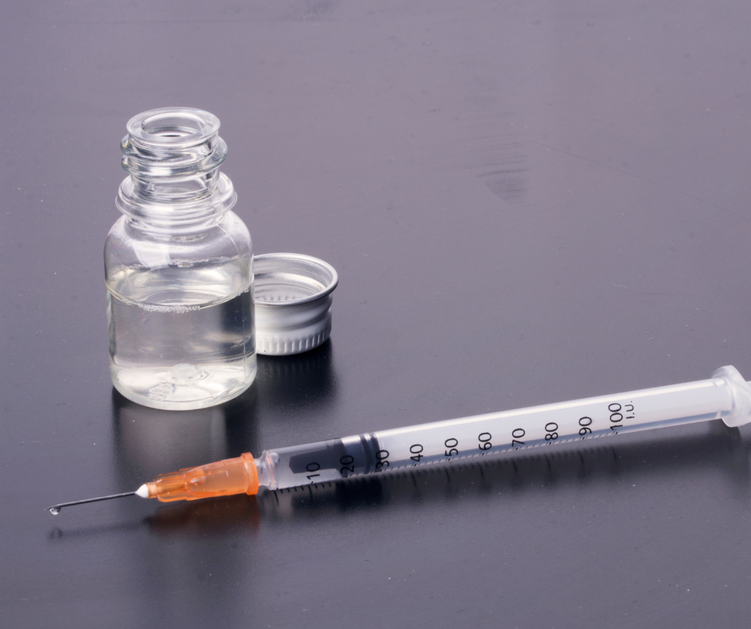 A syringe is next to a bottle of liquid on a table.