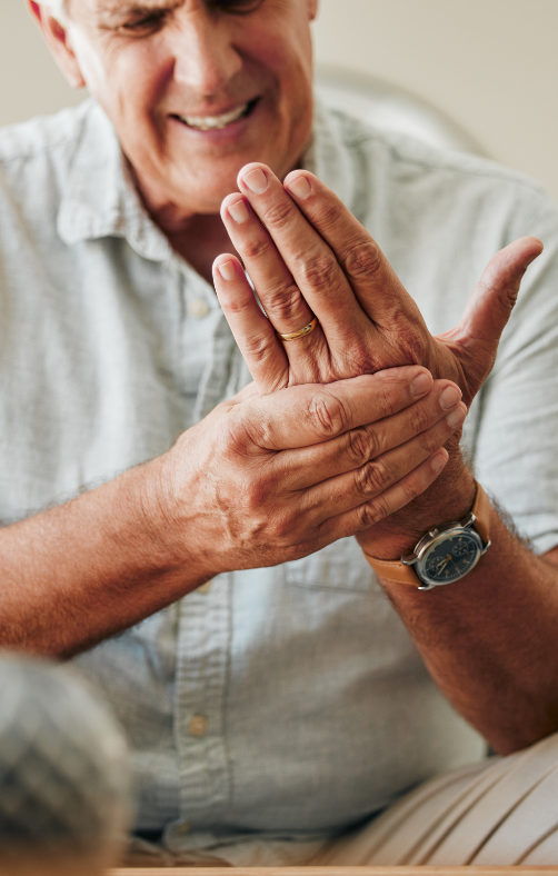 A man is rubbing his wrist while wearing a watch.