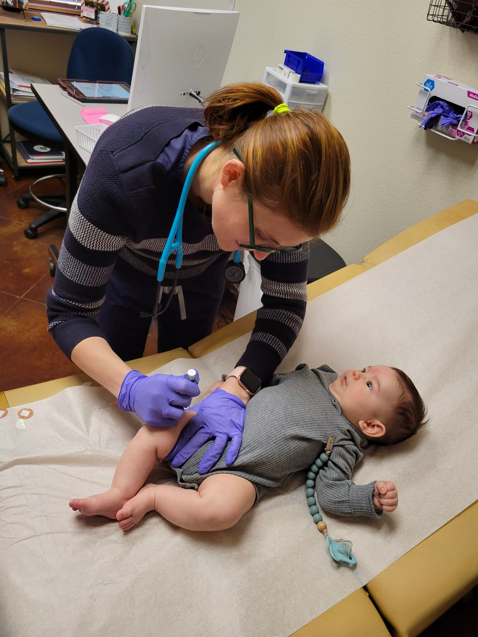A doctor is examining a baby 's leg with a stethoscope.