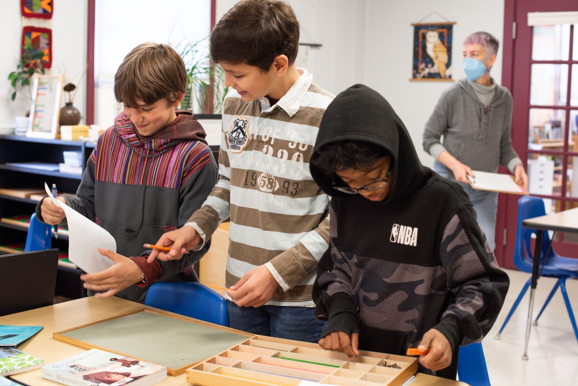 Children collaborating at a classroom table with papers and boards, focused on a hands-on activity