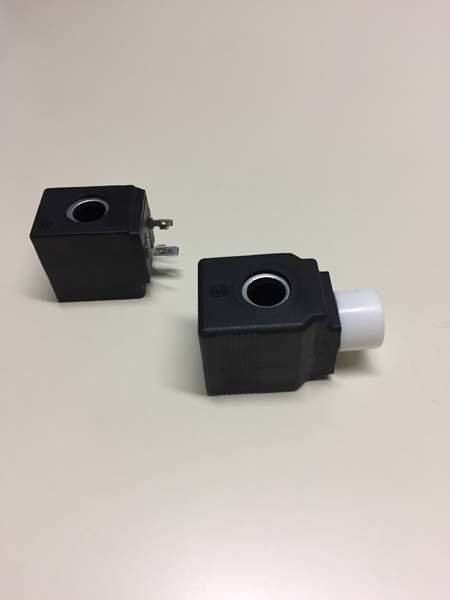 Due bobine solenoidi nere con fori centrali, una con connettore bianco e l'altra con perni, su una superficie bianca.