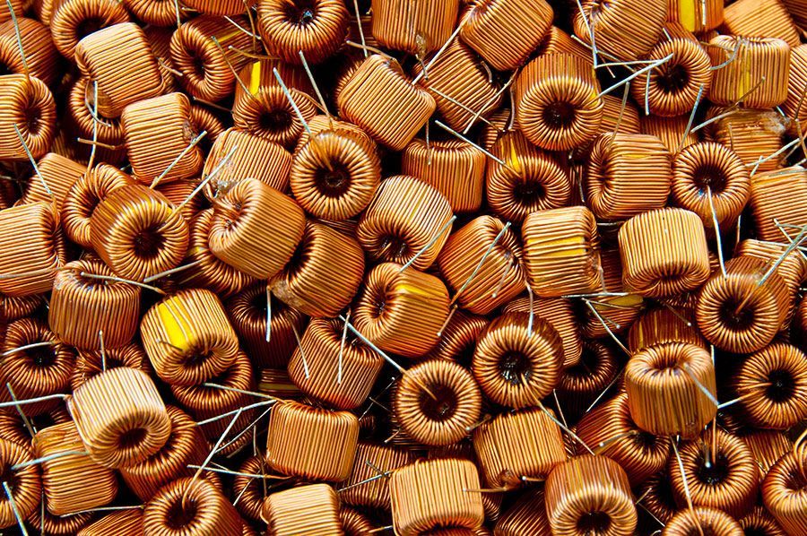 Pila di induttori cilindrici marroni con fili di collegamento, utilizzati in elettronica.
