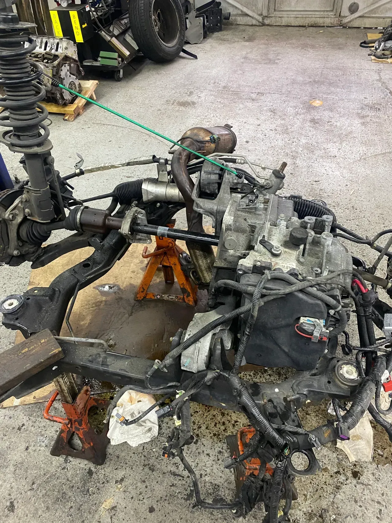 Damaged car engine and suspension parts on orange stands in a garage workshop
