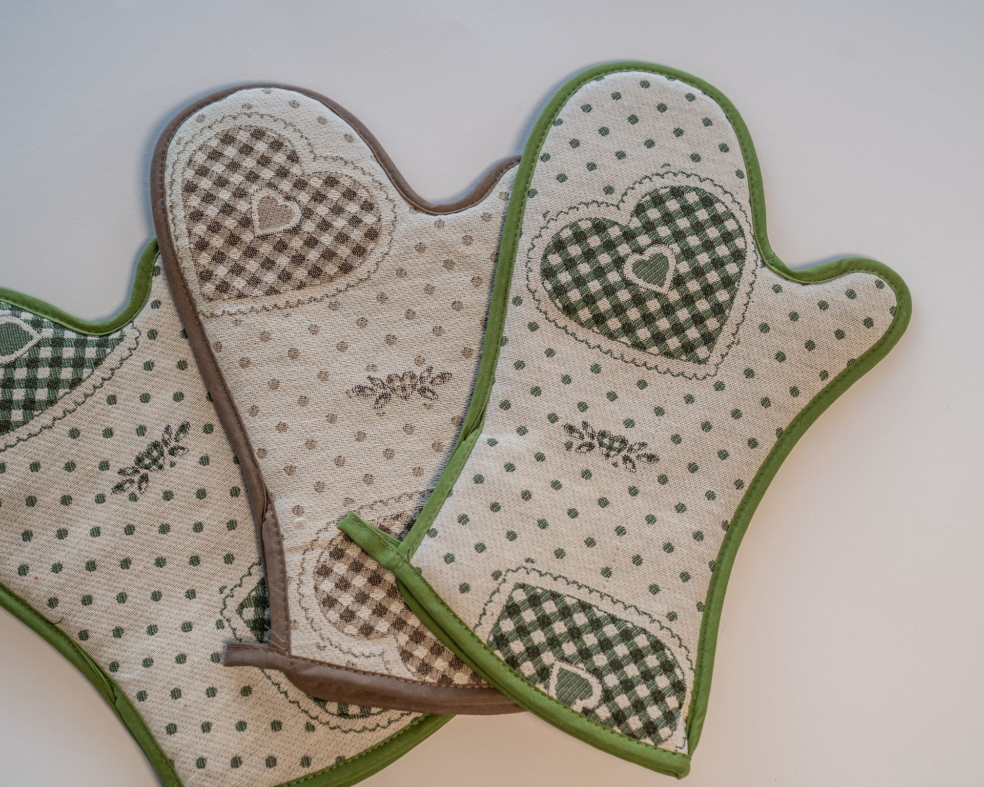 Tre presine beige e verdi con decorazioni a forma di cuore e quadretti a quadretti.