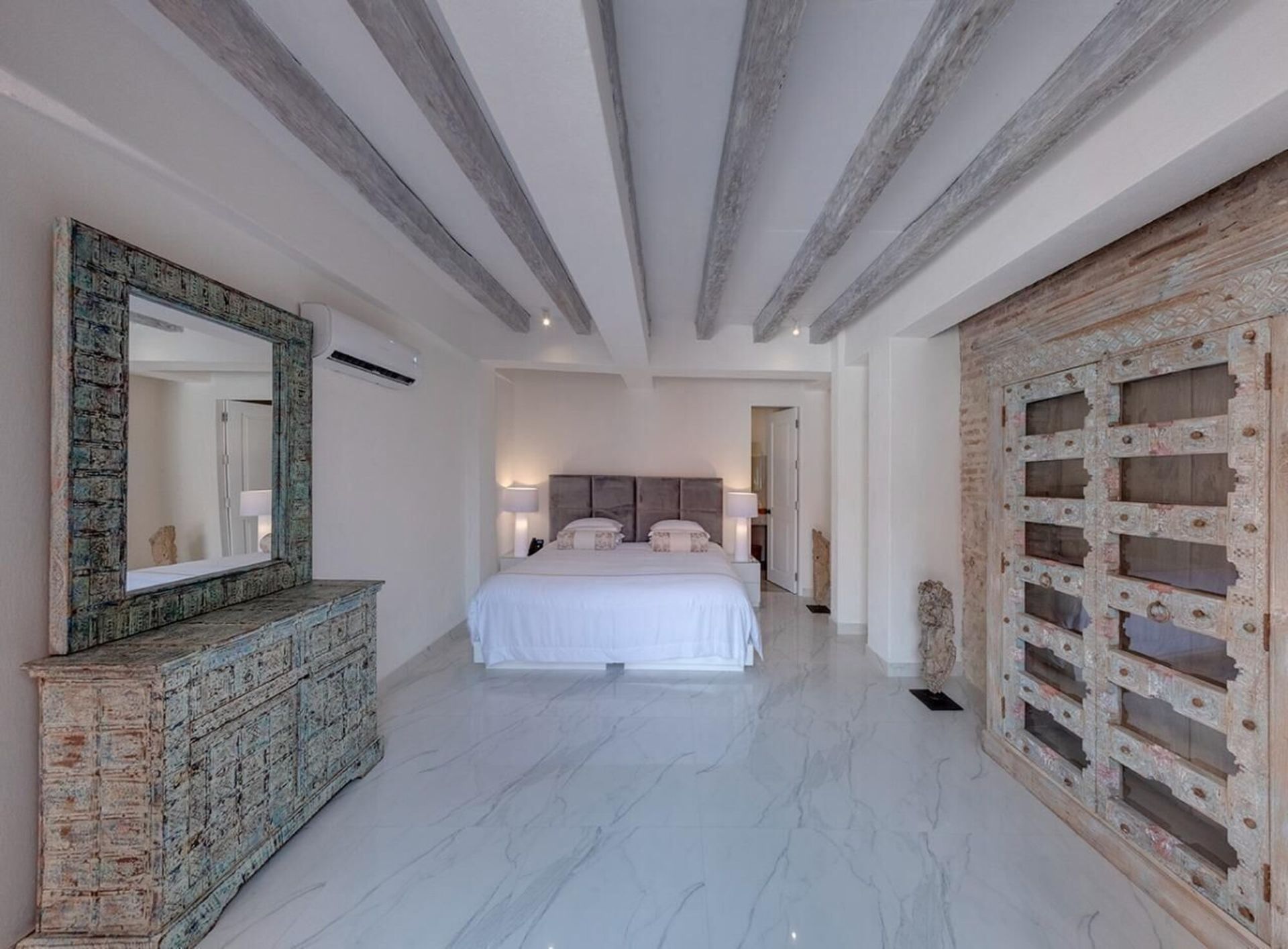 Un dormitorio con una cama grande, tocador y espejo.