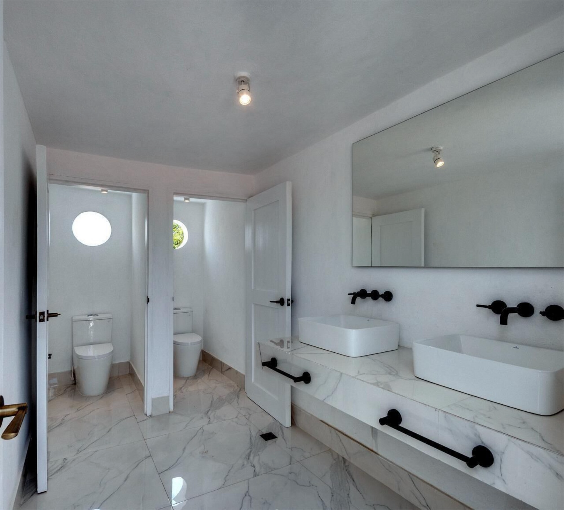 Un baño con dos lavabos y dos inodoros.
